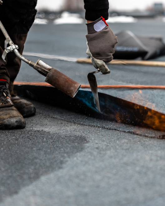 Image of a roofer working on a flat roof. 